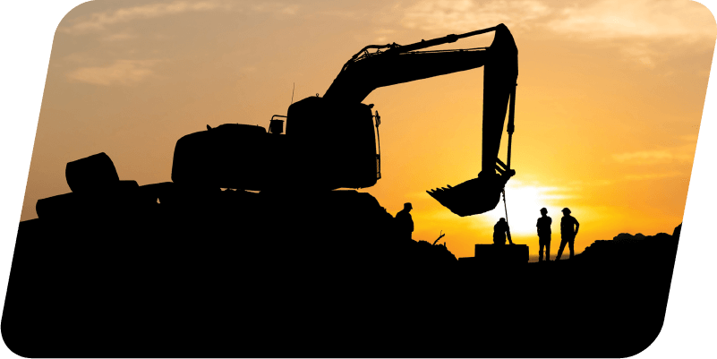 A construction crew working late in the evening by an excavator