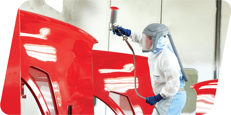 An autobody worker painting car body parts